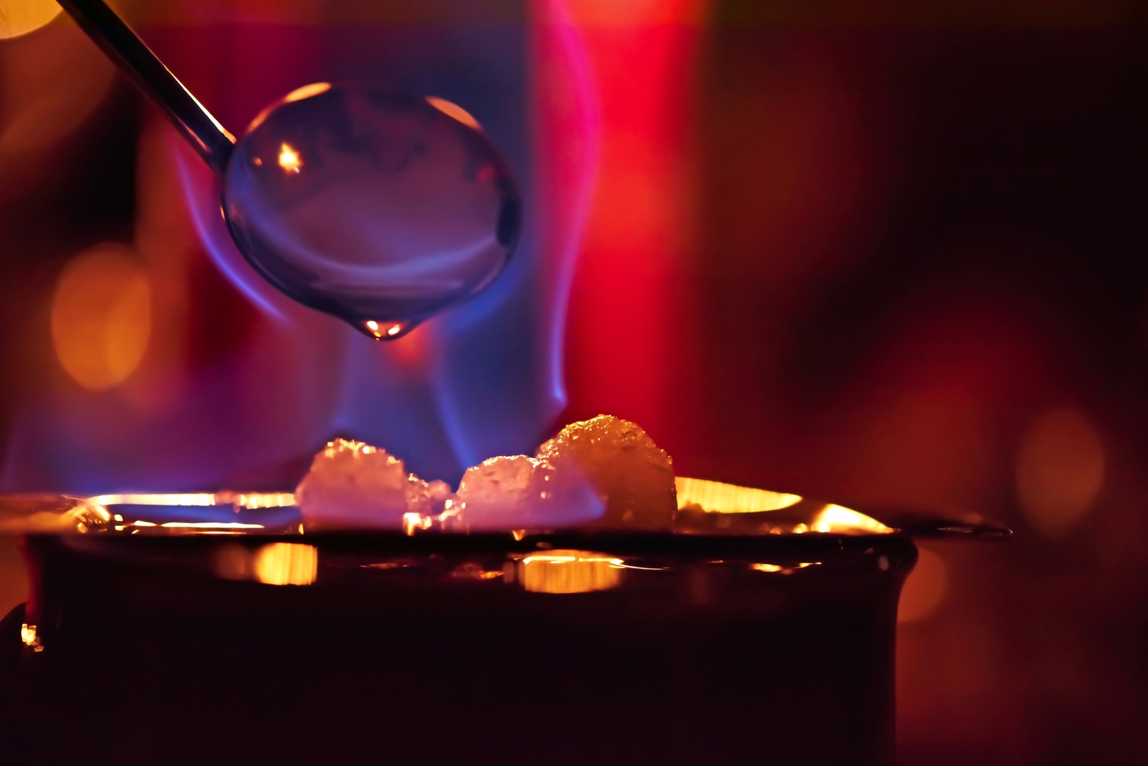 eine blaue Flamme ergießt sich über dem Zucker einer Feuerzangenbowle